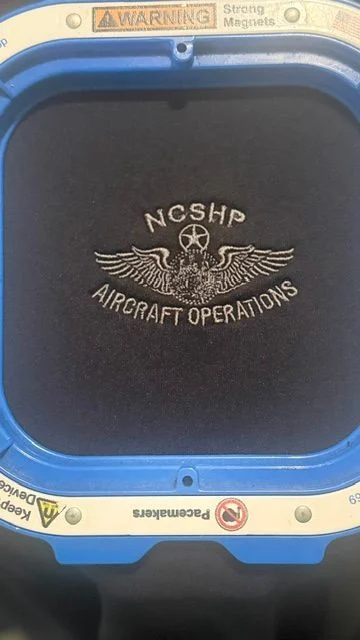 NCSHP Aircraft Operations embroidery held in a blue hoop